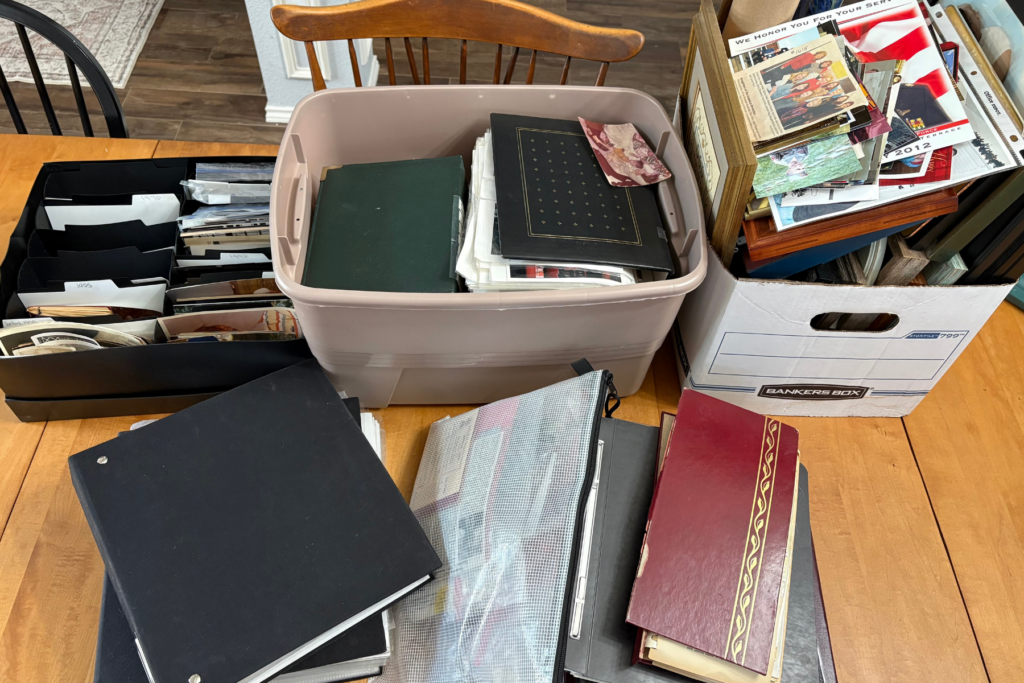 Boxes and albums of old family photos spread out on a dining table, ready for sorting family photos.