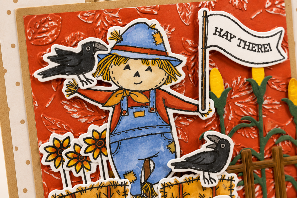 Close-up of a Fall Fun Fold Card featuring a hand-colored scarecrow created with Stampin' Blends and layered on an embossed autumn leaf background.