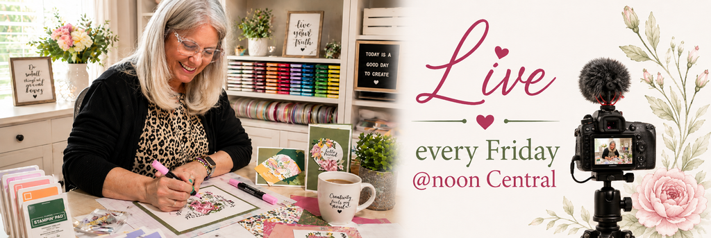Woman coloring a floral card at her craft desk surrounded by ink pads, ribbon, and cardstock, with 'Live every Friday @noon Central' graphic and a camera set up to film