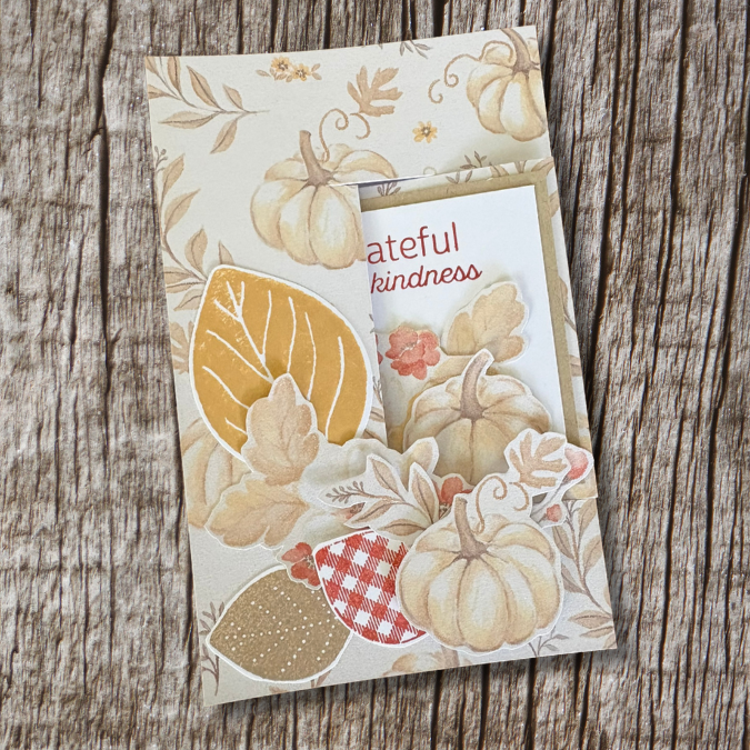 Close-up of fussy-cut pumpkins, leaves, and flowers layered on a fall card