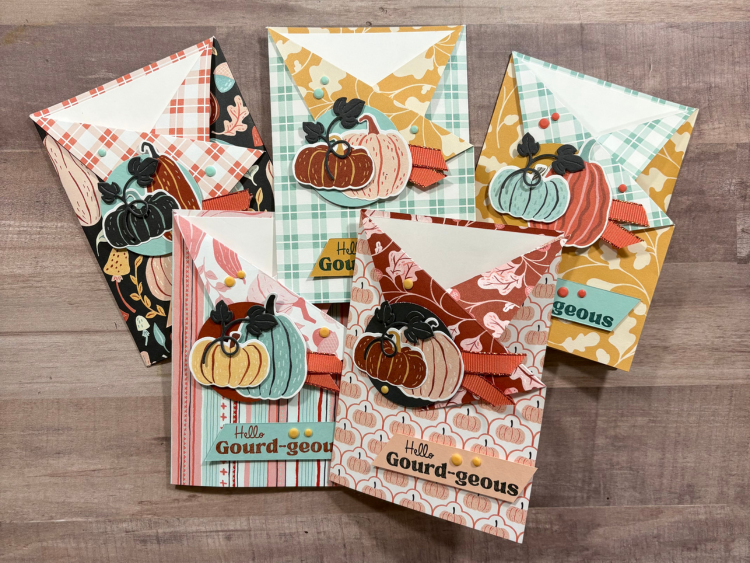 Five DIY birthday cards made assembly-line style using the same design with different patterned papers and pumpkin colors.