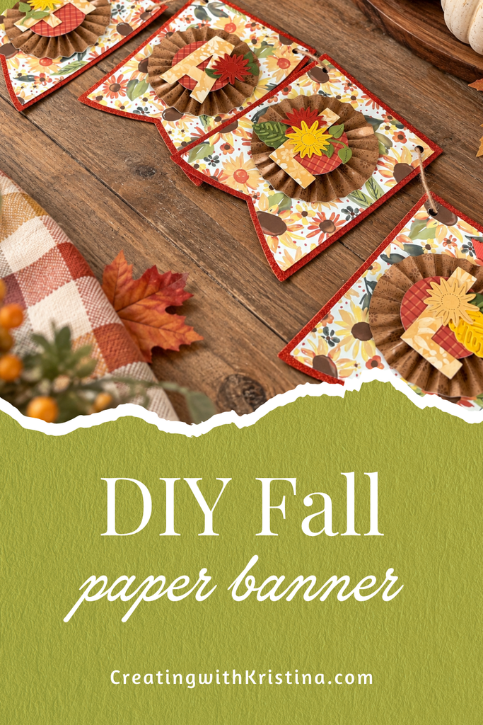 DIY Fall Paper Banner with paper rosettes, sunflower embellishments, and colorful fall patterned paper displayed on a rustic wood table.
